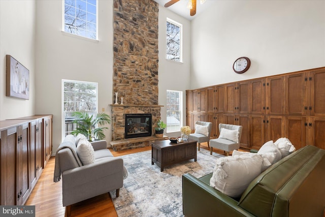 living area featuring a wealth of natural light, a fireplace, light wood finished floors, and ceiling fan