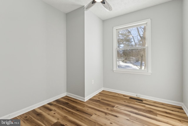 unfurnished room featuring hardwood / wood-style flooring, ceiling fan, and a textured ceiling