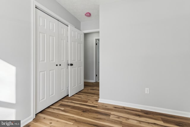 unfurnished bedroom with hardwood / wood-style floors, a textured ceiling, and a closet