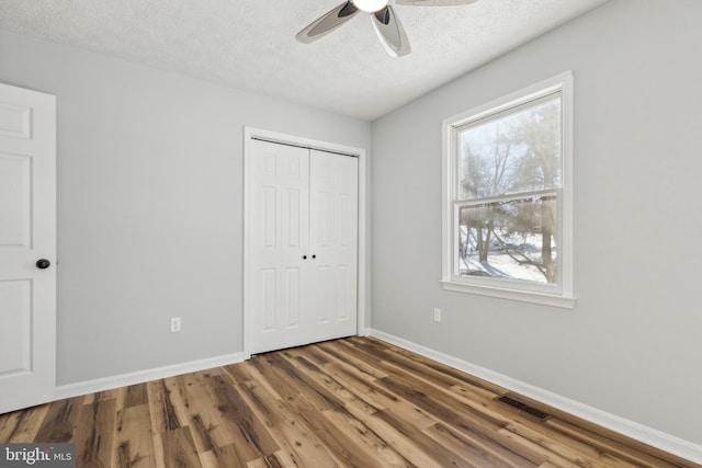 unfurnished bedroom featuring ceiling fan, dark hardwood / wood-style floors, a closet, and a textured ceiling