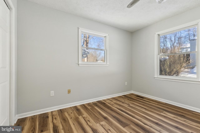 unfurnished bedroom with multiple windows, ceiling fan, hardwood / wood-style flooring, and a textured ceiling