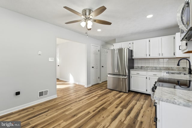 kitchen with sink, white cabinetry, tasteful backsplash, hardwood / wood-style flooring, and stainless steel appliances