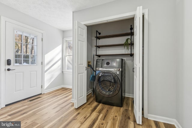 laundry room featuring washer / dryer, a textured ceiling, and light wood-type flooring