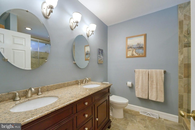 bathroom featuring visible vents, a sink, toilet, and tiled shower