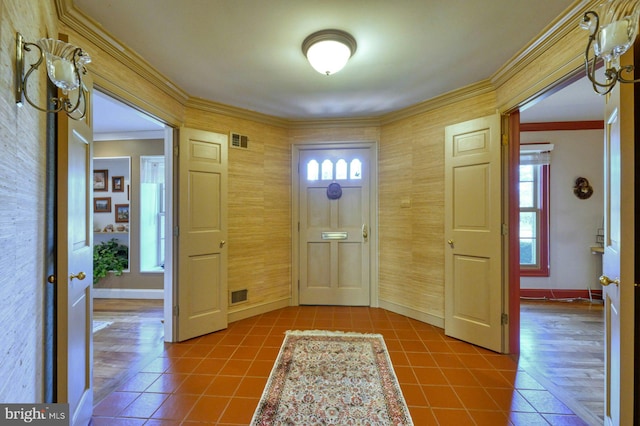 tiled entrance foyer with baseboards, visible vents, and crown molding