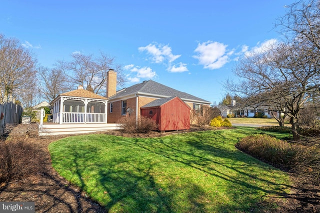 back of property with brick siding, fence, a gazebo, a lawn, and a chimney