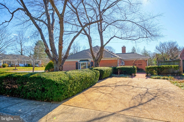 view of front of home featuring brick siding, fence, and a chimney