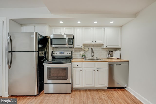 kitchen featuring tasteful backsplash, white cabinetry, sink, stainless steel appliances, and light hardwood / wood-style flooring