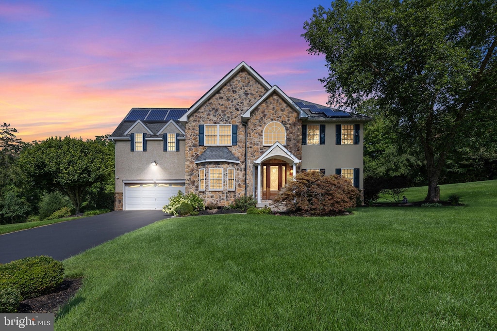 view of front of house featuring a yard, a garage, and solar panels