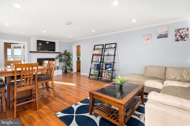 living room with ornamental molding, a brick fireplace, and light hardwood / wood-style floors