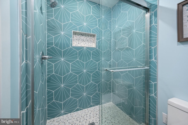 bathroom with a shower with shower door and toilet