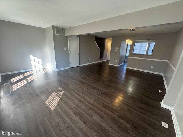 unfurnished living room with an inviting chandelier and dark wood-type flooring