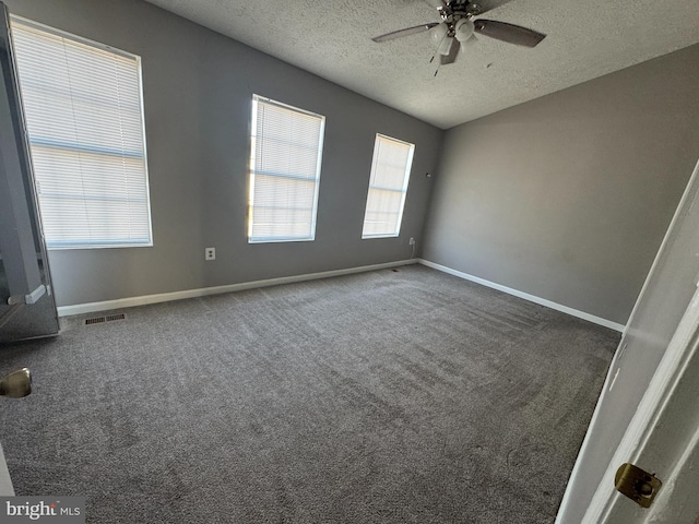 unfurnished room with ceiling fan, a textured ceiling, and dark colored carpet