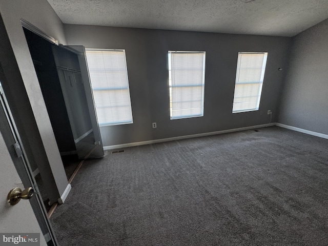 unfurnished bedroom featuring dark carpet and a textured ceiling