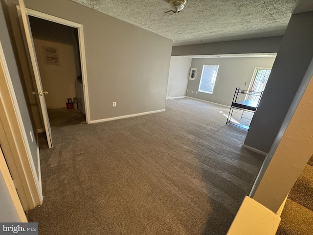 unfurnished room featuring dark carpet and a textured ceiling