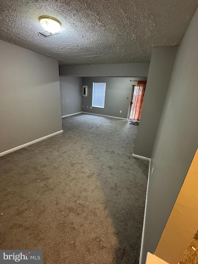 empty room with a textured ceiling and dark colored carpet