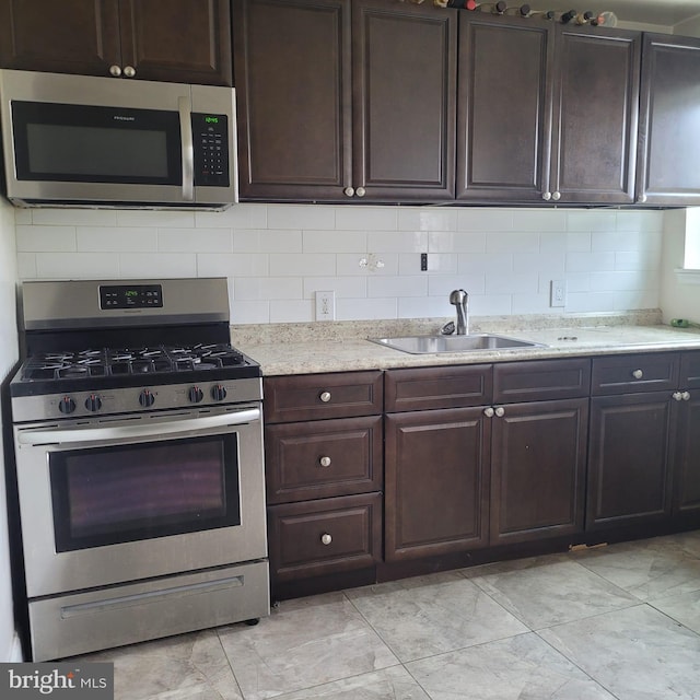 kitchen featuring stainless steel appliances, tasteful backsplash, sink, and dark brown cabinetry