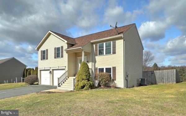 bi-level home featuring cooling unit, a garage, and a front lawn