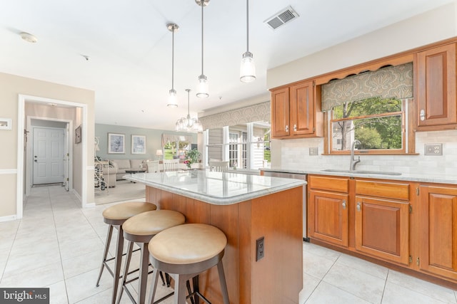 kitchen featuring a sink, a kitchen breakfast bar, light tile patterned floors, backsplash, and visible vents
