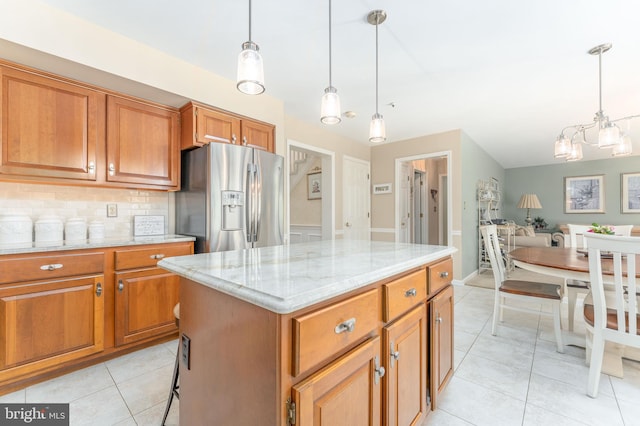 kitchen with brown cabinets, stainless steel fridge with ice dispenser, a chandelier, decorative backsplash, and light tile patterned floors