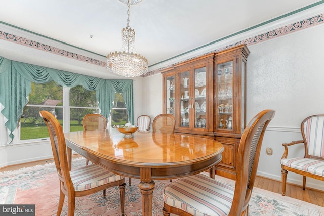 dining room featuring an inviting chandelier, baseboards, and light wood-type flooring