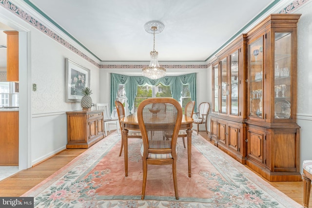 dining space featuring crown molding, a notable chandelier, and light wood-type flooring