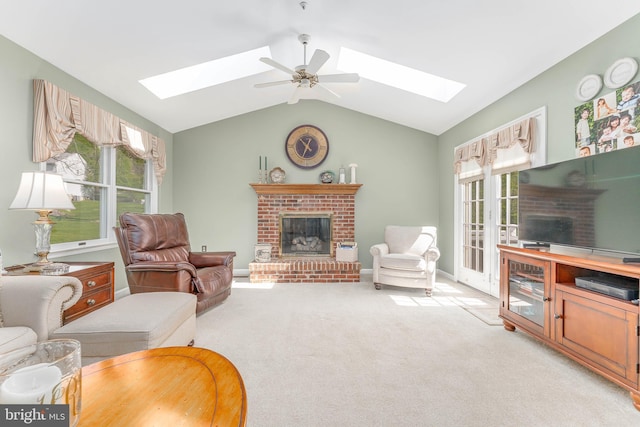 living area with a brick fireplace, light carpet, a healthy amount of sunlight, and vaulted ceiling with skylight