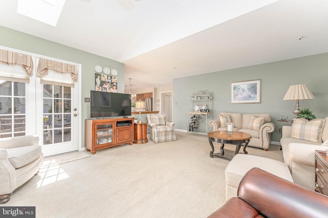 carpeted living room featuring baseboards and lofted ceiling with skylight