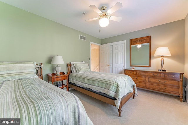 bedroom with ceiling fan, visible vents, light carpet, and a closet