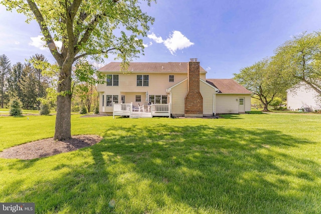 rear view of house featuring a lawn, a wooden deck, and a chimney