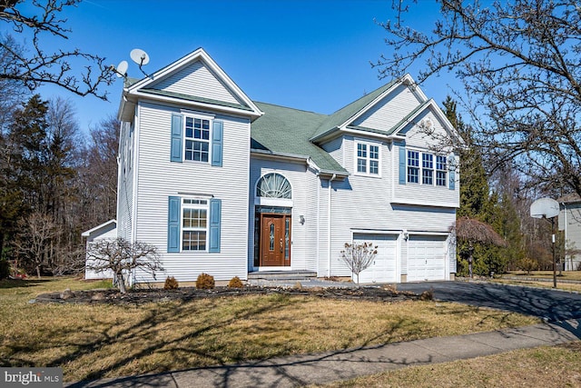 traditional-style house featuring a front lawn, an attached garage, and driveway