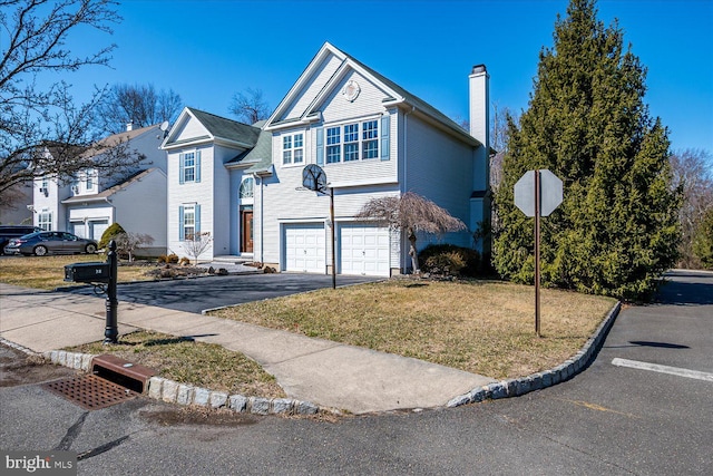 view of front facade with a garage, driveway, a chimney, and a front yard