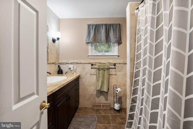 bathroom featuring a wainscoted wall, tile walls, visible vents, vanity, and tile patterned floors