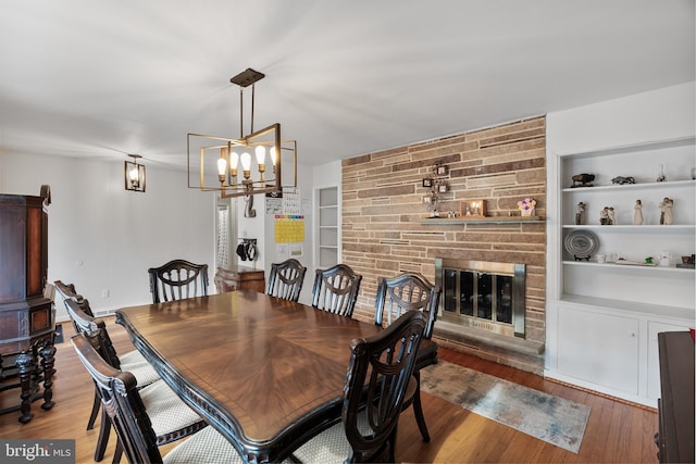 dining space with a fireplace, wood finished floors, and built in features