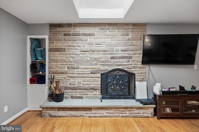 living area featuring a large fireplace, wood finished floors, and baseboards