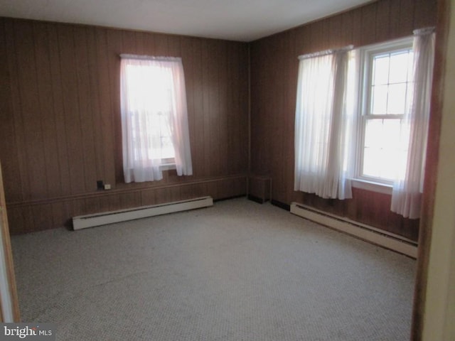 empty room featuring wooden walls, carpet, and baseboard heating