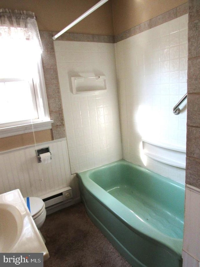 bathroom with a baseboard heating unit, tiled shower / bath combo, and toilet