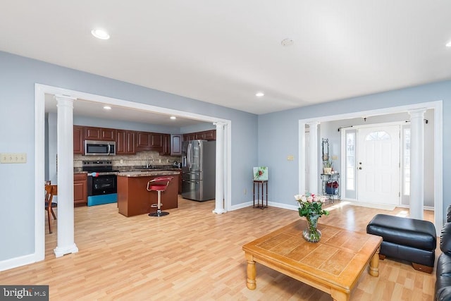 living room with light wood-type flooring, decorative columns, baseboards, and recessed lighting