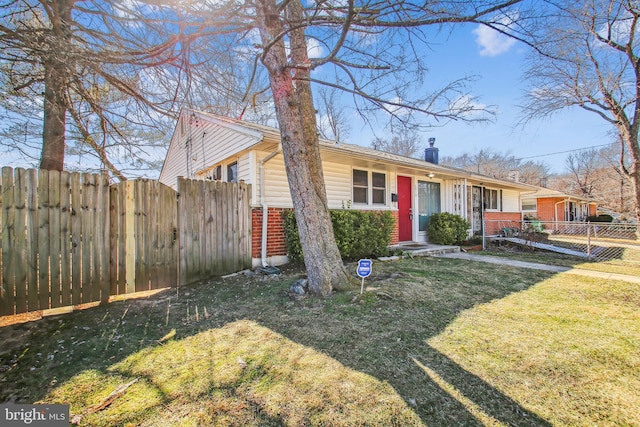 view of front of house with brick siding, fence, a chimney, and a front lawn