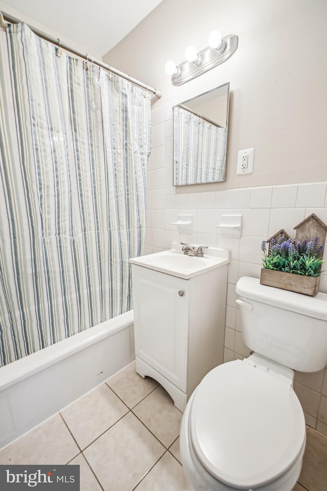 bathroom featuring toilet, tile patterned floors, shower / bathtub combination with curtain, vanity, and tile walls