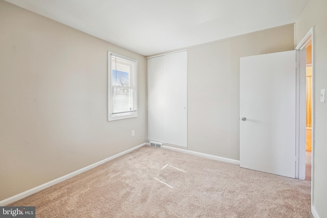 unfurnished room with light carpet, visible vents, and baseboards