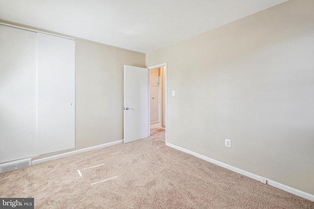 unfurnished bedroom with baseboards, visible vents, a closet, and light colored carpet