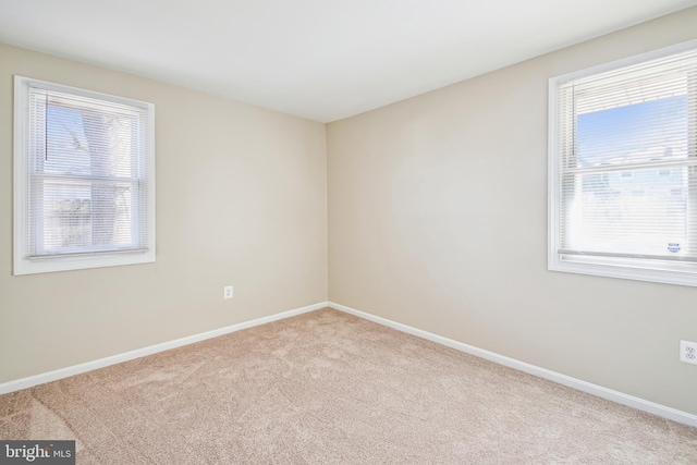 unfurnished room featuring light carpet and baseboards