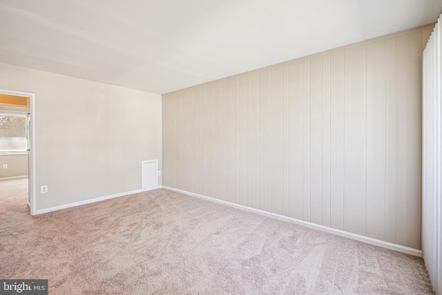 empty room featuring light colored carpet and baseboards