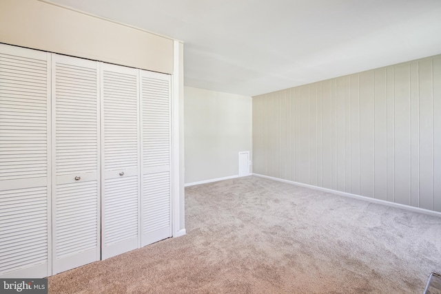 unfurnished bedroom featuring baseboards, a closet, and light colored carpet