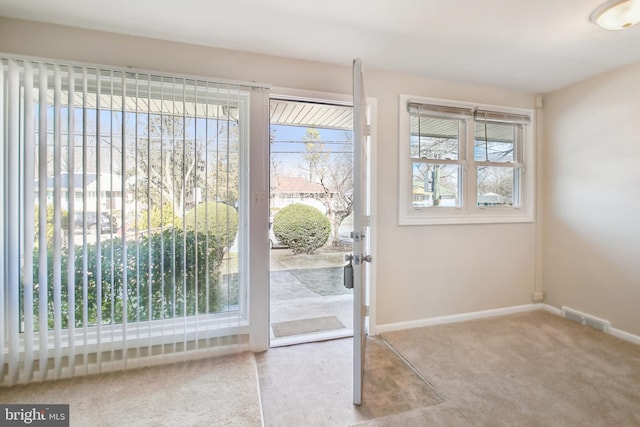 doorway with light colored carpet, visible vents, and baseboards