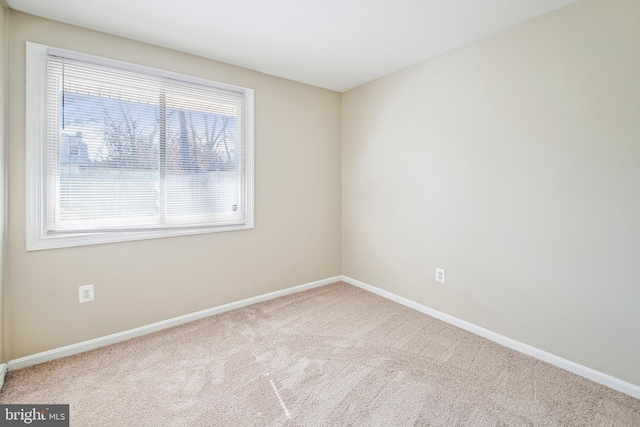 empty room featuring light carpet and baseboards