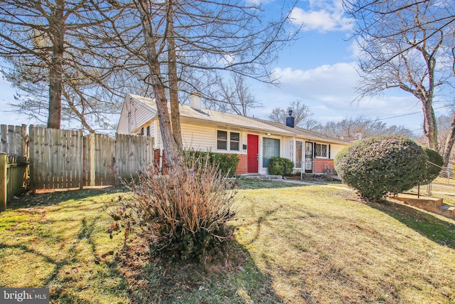 view of front of house featuring a chimney, fence, a front lawn, and brick siding