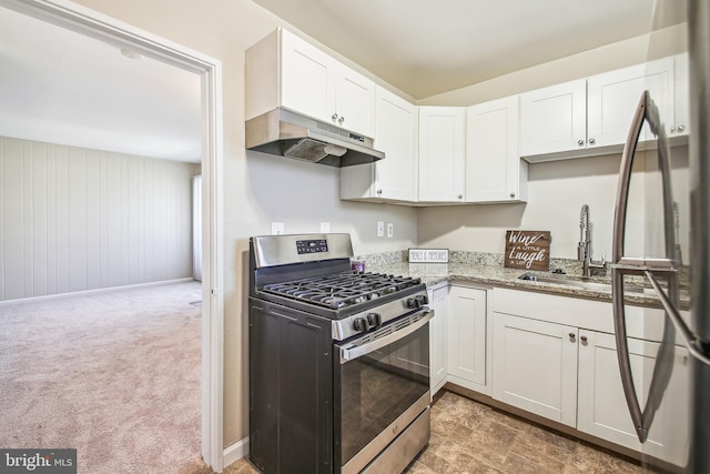 kitchen with light stone countertops, under cabinet range hood, stainless steel range with gas cooktop, and white cabinetry