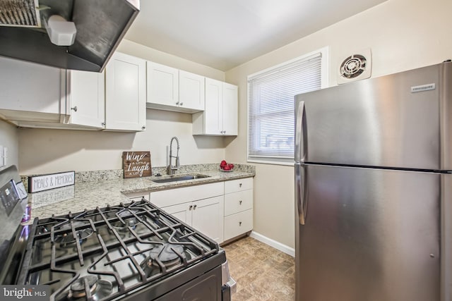 kitchen with black gas range, freestanding refrigerator, light stone countertops, white cabinetry, and a sink